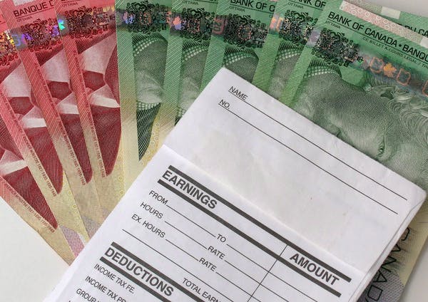 A fan of Canadian banknotes with a notepad resting on top