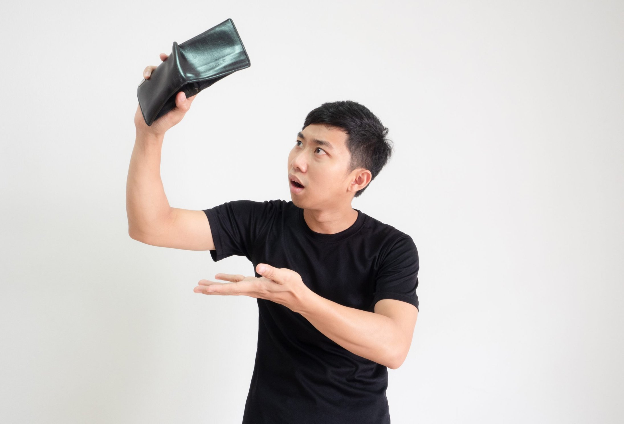 Surprised man looks at his empty wallet in shock